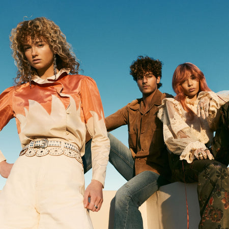 Three people posing outdoors with a clear blue sky.